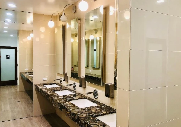 Double-sink stone vanity with tall mirrors and globe lights in the Kaqun LA facilities