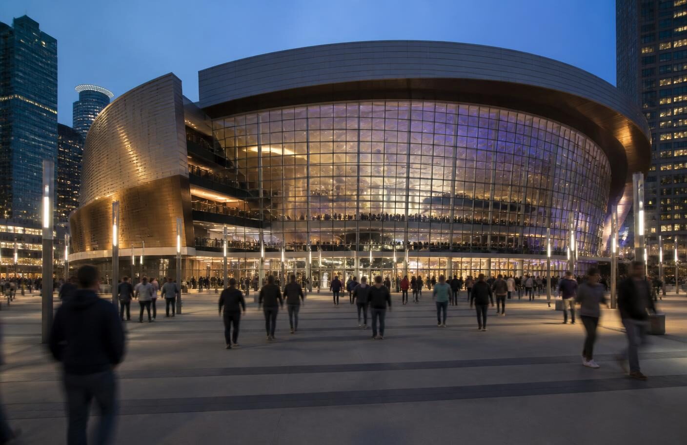 Crowds walking a lit plaza in front of a downtown arena at dusk, the event nights that fill Downtown Los Angeles hotels